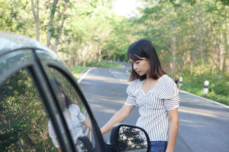 Asian woman Check for broken cars on the roads around the forest.の写真素材