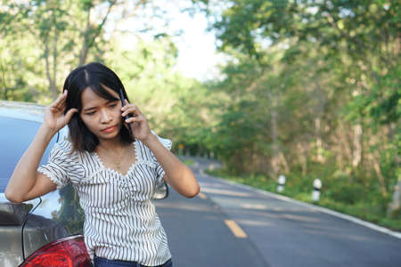 Asian woman Call a mechanic, the car goes out on the road around the forest.の写真素材