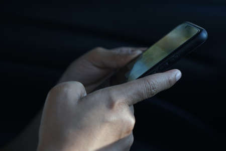 human hand is playing a smartphone in bright lightの写真素材