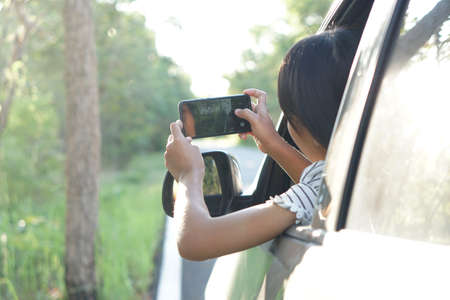 Asian women use their smart phones to take pictures of nature, the concept of love the world, traveling on a car.の写真素材