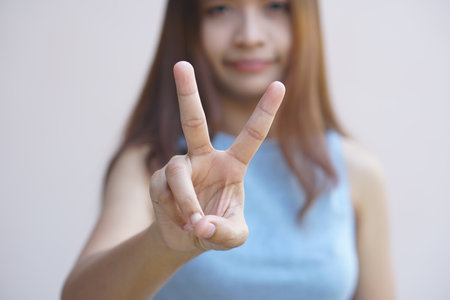 Woman holding up two fingers to symbolize fighting
