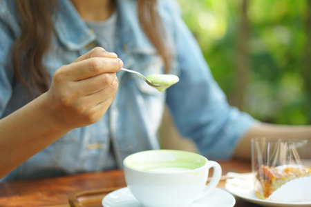 Woman using spoon to scoop hot green tea