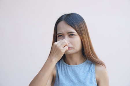 Asian woman covering her nose with her hands due to a bad smellの写真素材
