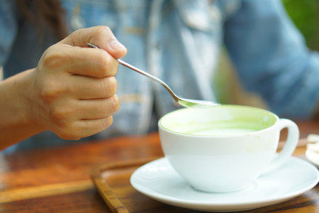 Woman using spoon to scoop hot green teaの写真素材
