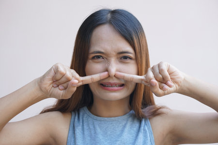 Asian woman covering her nose with her hands due to a bad smellの写真素材