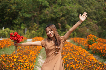 Asian woman smiling happily among beautiful flowersの写真素材
