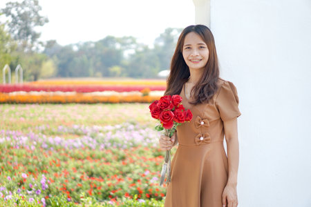 Asian woman smiling happily among beautiful flowersの写真素材