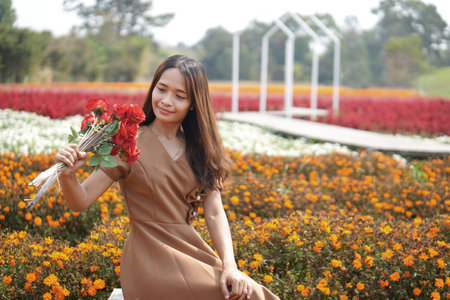 Asian woman smiling happily among beautiful flowersの写真素材