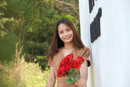 Asian woman smiling happily among beautiful flowersの写真素材