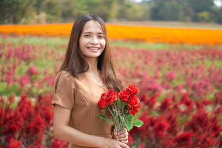 Asian woman smiling happily among beautiful flowersの写真素材