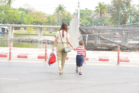 mother takes her child to walk across the street.の写真素材