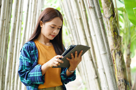 female farmer is happy after viewing results from a laptop computer. banana plantation backgroundの写真素材