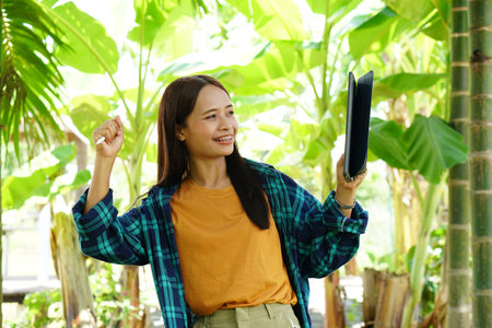 female farmer is happy after viewing results from a laptop computer. Increased profitsの写真素材