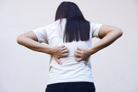 Backside of white woman back pain and ache conceptの写真素材