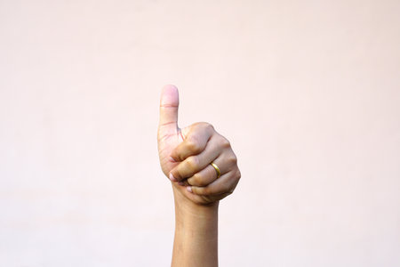 Asian woman's hand raising thumbs as a sign of greatnessの写真素材