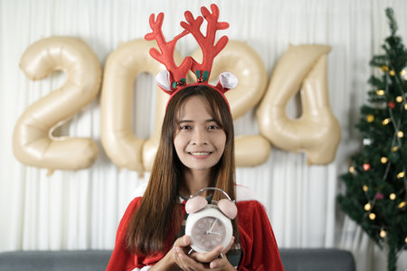 Asian woman holding a watch Have fun celebrating Christmas 2024. Decorate and decorate the room with...