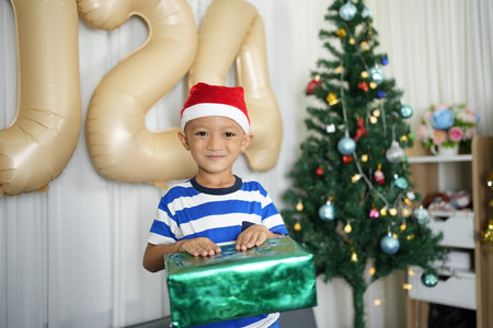Merry Christmas 2024 concept A boy holding a gift box is happy to receive a present on Christmas...