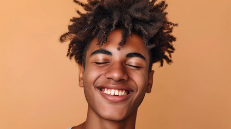 Happy young African American gen z guy winking isolated on beige background. Playful ethnic teen student, cool curly generation z teenager smilingの素材