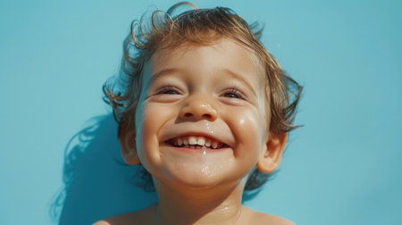Portrait of happy joyful laughing beautiful little boy on blue backgroundの素材