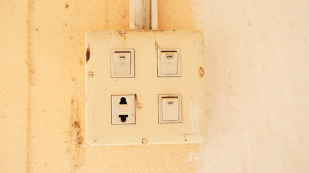 An aged electrical switch plate exhibits wear and dust on a wall surface, highlighting vintage design and the need for maintenance in domestic spaces.の写真素材