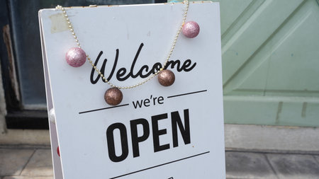 A charming welcome sign featuring an open message and decorative accents, perfect for attracting customers to a small business or retail shop.の写真素材