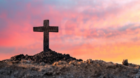 Wooden cross stands prominently on mound of earth against vibrant gradient sky, evoking sense of peace and reflection. colors of sunset create serene backdrop, enhancing spiritual atmosphereの素材