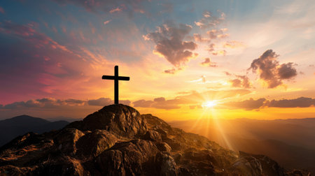 Silhouette of cross on rocky mountain peak against vibrant sunset sky, with warm colors illuminating horizon, evokes sense of peace and reflectionの素材