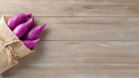 A burlap sack filled with fresh purple sweet potatoes rests on a wooden table, highlighting the natural beauty and health benefits of this root vegetable. Perfect for cooking.の素材