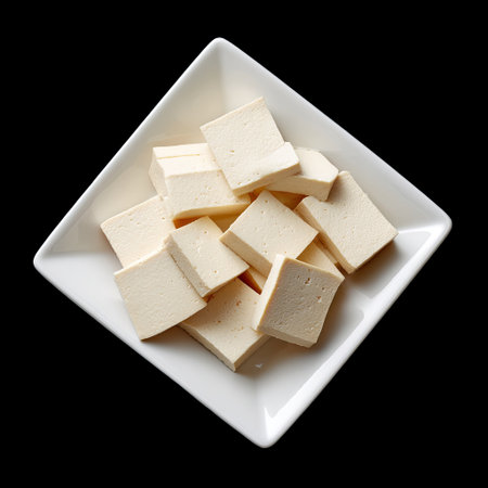 A visually appealing arrangement of freshly cut tofu cubes placed on a sleek square plate against a black background, perfect for culinary inspiration.の素材