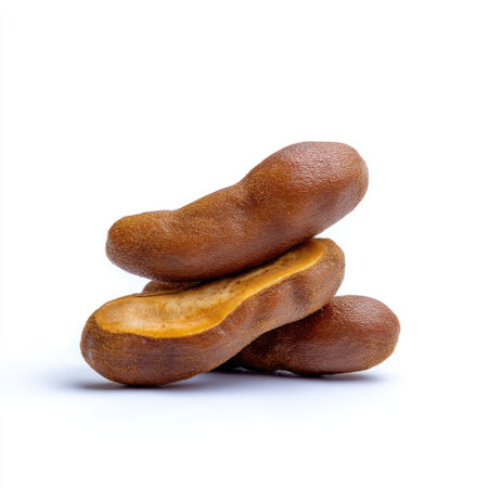 This image showcases vibrant tamarind pods stacked creatively against a pristine white backdrop, perfect for food-related projects and promotions.の素材
