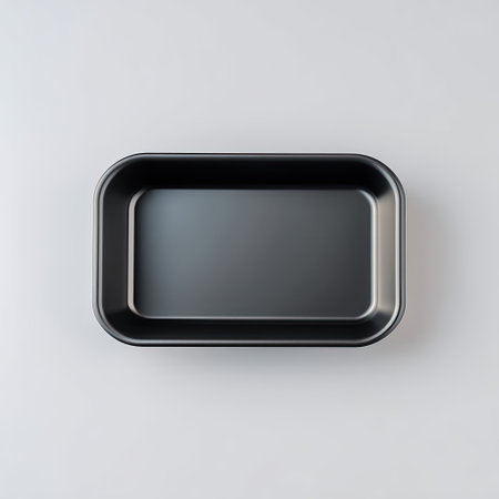 A sleek rectangular black baking pan stands empty on a smooth light surface, ideal for various culinary preparations and kitchen tasks.の素材