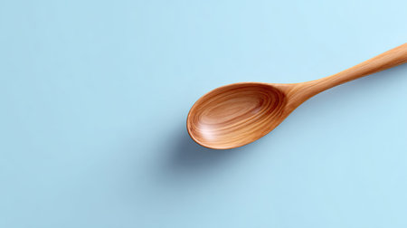A beautifully crafted wooden spoon rests elegantly on a soft blue surface, showcasing its smooth texture and natural grain, ideal for culinary aesthetics.の素材