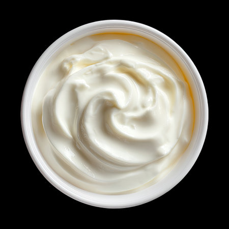This image showcases a creamy white substance in a round container, displaying its smooth and glossy texture against a stark black background. Perfect for culinary uses.の素材