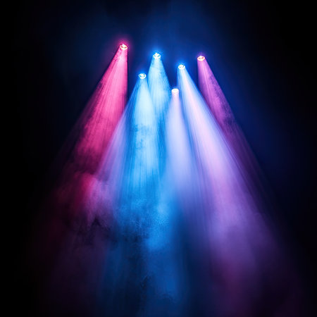 Abstract beams of multicolored stage lights crossing through smoke in dark concert hallの素材