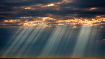 Captivating scene of sunlight streaming through dark clouds over the ocean, creating a breathtaking display of nature's beauty at sunset, fostering peace and tranquility.の素材