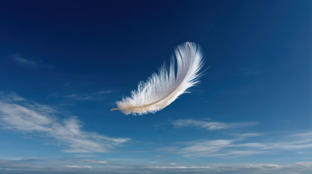 A beautiful white feather captures the essence of lightness, gracefully floating against a vivid blue sky adorned with soft clouds, evoking a sense of peace and tranquility.の素材