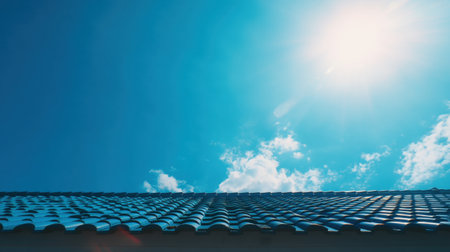 A captivating view of a blue sky illuminated by bright sunlight, featuring a textured rooftop in perspective. Ideal for conveying tranquility and freshness in design.の素材