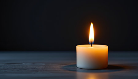 A solitary candle burns gently in a dark environment, creating a serene ambiance ideal for meditation or relaxation. The flickering flame symbolizes tranquility and warmth, inviting a peaceful atmosphere for mindfulness practices.の素材
