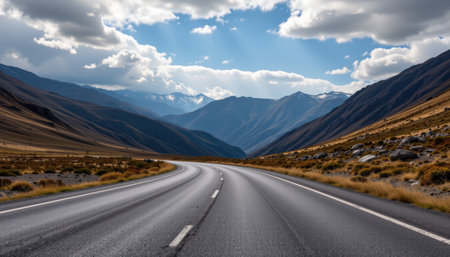 A captivating image of a winding road leading through majestic mountains under a dramatic sky. This serene landscape evokes feelings of adventure and exploration.の素材