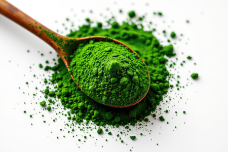 Close-up view of green powder displayed on a wooden spoon with a vibrant green backdrop, symbolizing health, nutrition, and wellness in food preparation.の素材