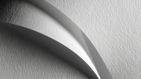 A close-up view of a textured grey paper surface featuring a delicate curved crease, creating an artistic and minimalistic style ideal for backgrounds and designs.の素材