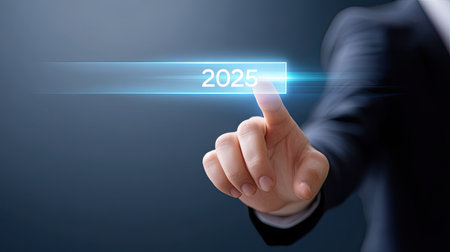 An image depicts business leader hand pressing glowing button labeled 2025, symbolizing progress and innovation. this visual conveys sense of forward thinking and ambitionの素材