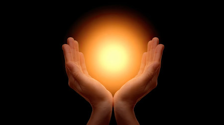 A captivating image of two hands gently cradling a glowing sphere of light, set against a black background, symbolizing hope, energy, and creativity.の素材