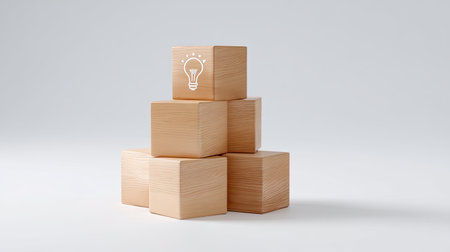 This image features a stack of smooth wooden blocks arranged in a minimalist style, with a light bulb symbol depicting creativity and innovation, perfect for design projects.の素材