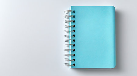 A vibrant blue spiral notebook positioned on a light surface, ideal for showcasing stationery options, creative writing, or minimalist desk setups.の素材