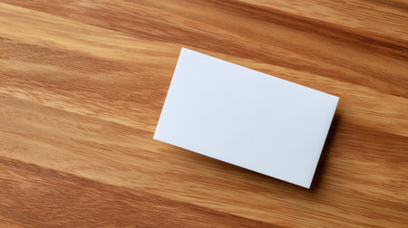 A blank business card rests on a wooden table, offering an ideal canvas for branding and customization. Perfect for marketing concepts and professional presentations.の素材