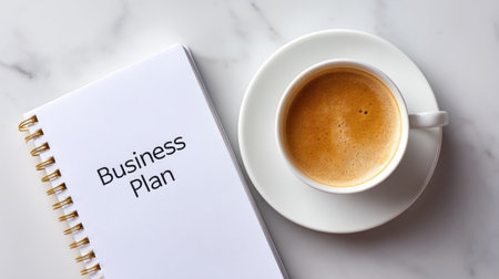 A clean marble surface features a business plan notebook and a coffee cup, symbolizing professionalism and creativity in planning. Perfect for workspace inspiration.の素材