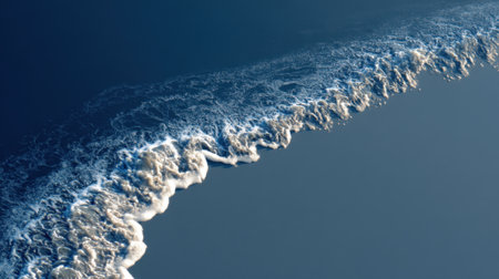 This captivating aerial view depicts soft ocean waves gently crashing against the shore, creating a serene interplay of light, shadow, and texture on the water's surface.の素材