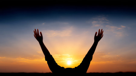 A silhouette of raised hands against glowing sunrise, symbolizing hope and new beginnings. vibrant colors of sky create inspiring atmosphereの素材