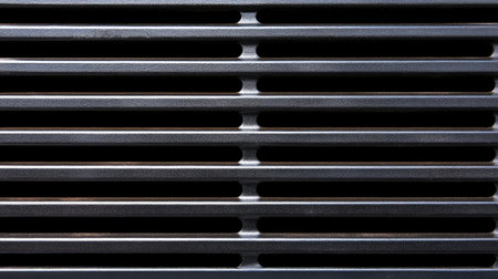 Abstract view of a sleek metal vent cover featuring horizontal slits. The industrial design highlights light and shadows, creating a modern aesthetic for various applications.の素材
